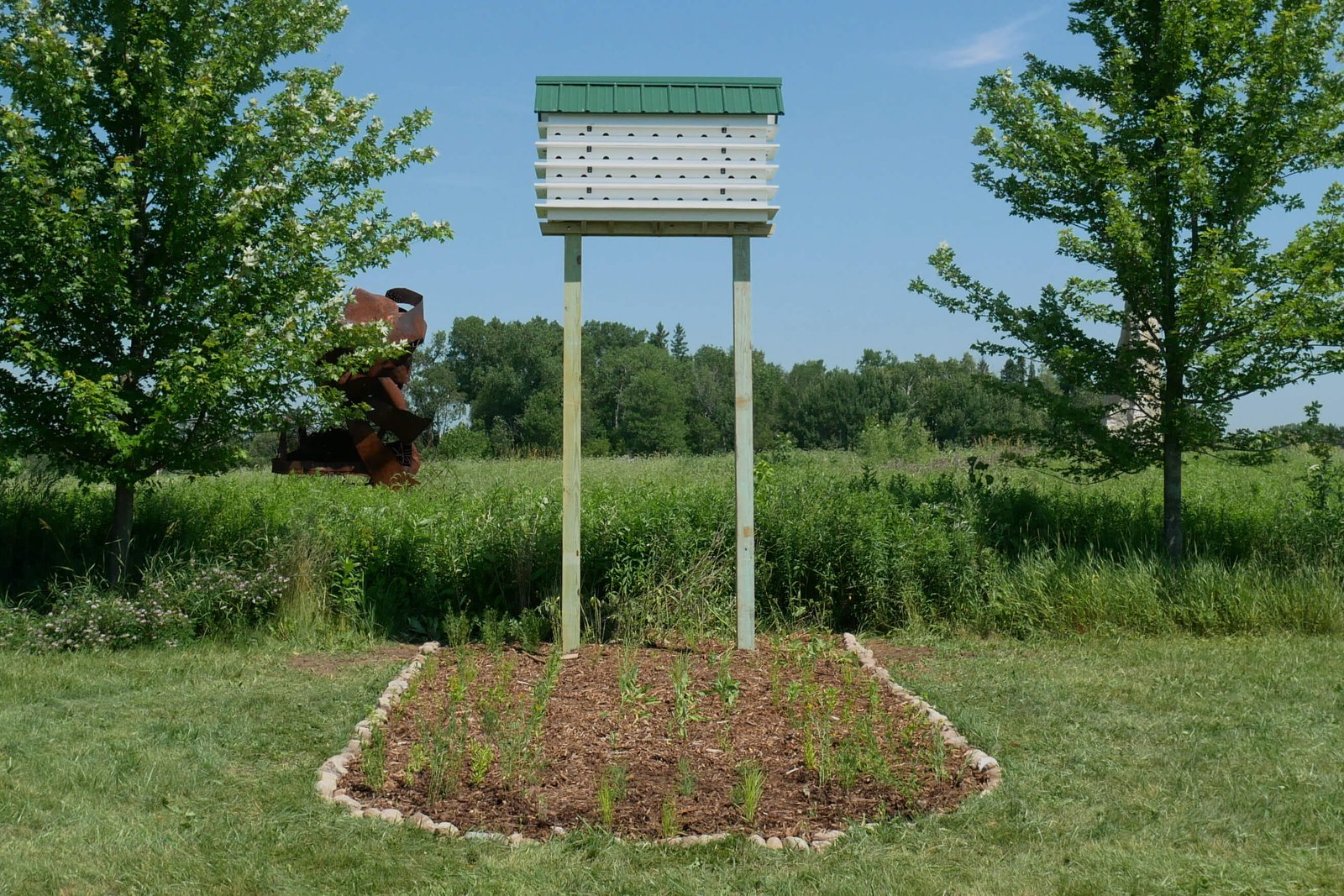 A praire garden in the shape of a basketball free throw lane and a purple martin house